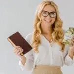 beautiful blond woman holding a jar of money and a book of business to demonstrate income producing assets