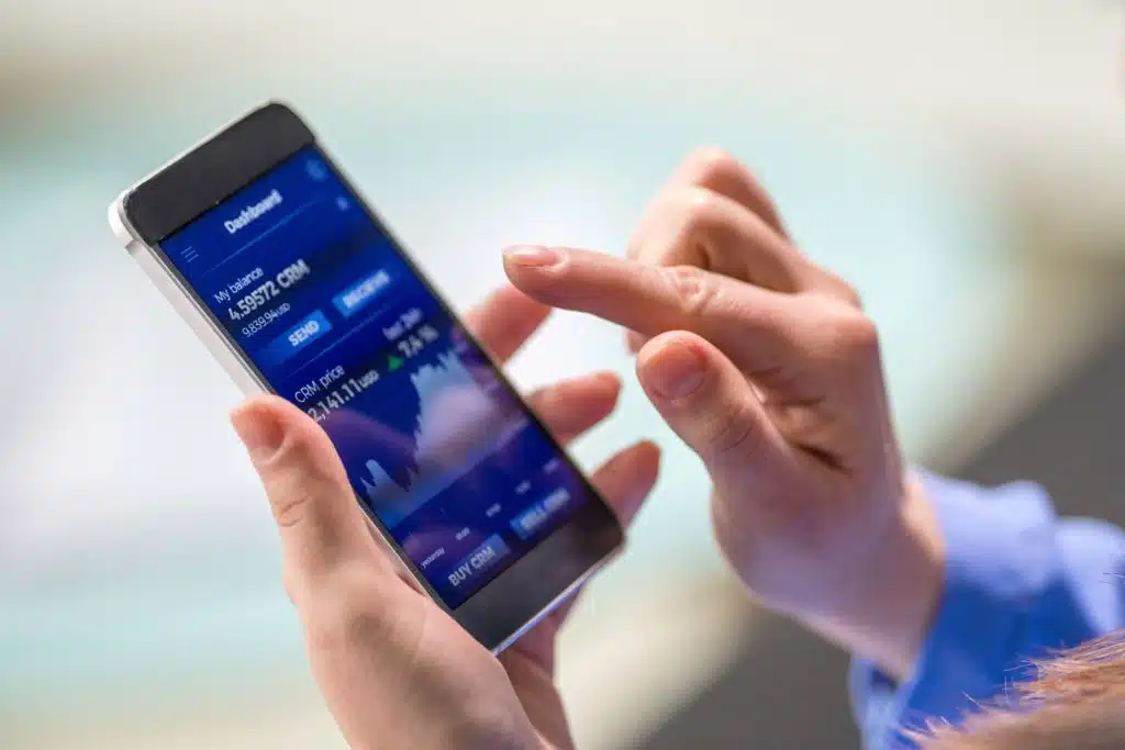 A closeup of a hand holding a mobile phone open to an investing app