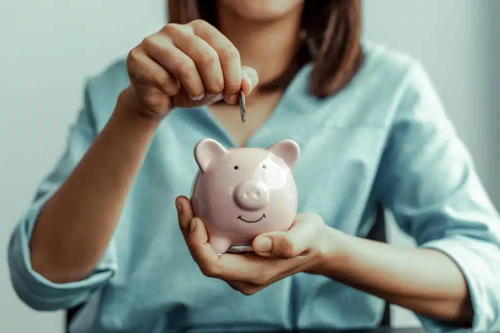 woman seated dropping a quarter into a piggy bank