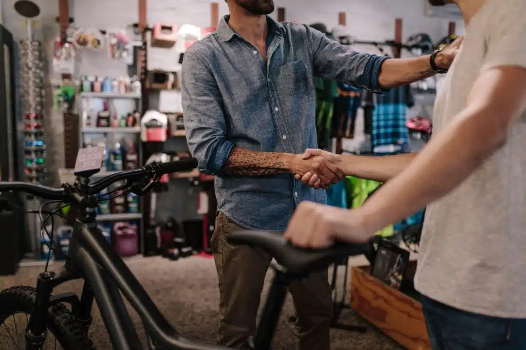 two men shaking hands one is holding a bike